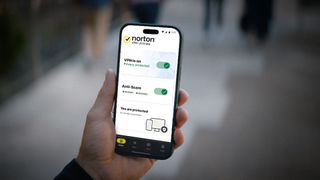 A mobile phone in a person's hand shows the Norton VPN app.