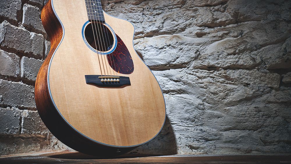 A Taylor acoustic guitar leaning against a brick wall