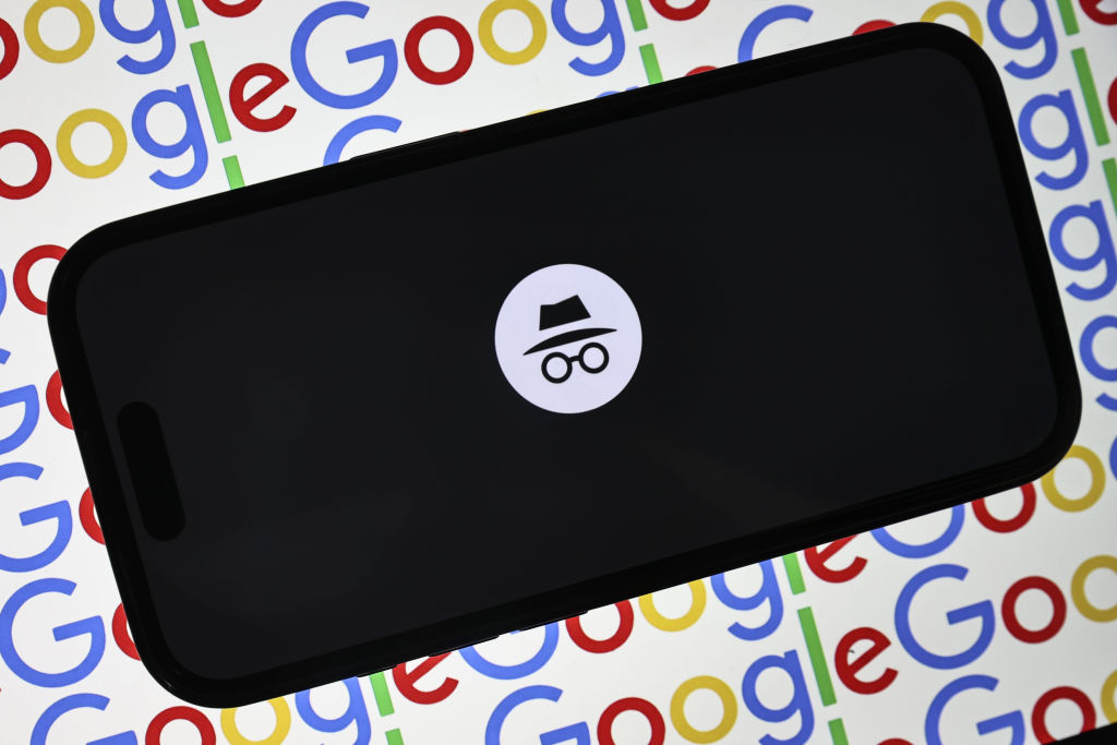 A Google Incognito Mode tab open on a mobile phone, set against a multi-color background made up of a repeating Google logo.