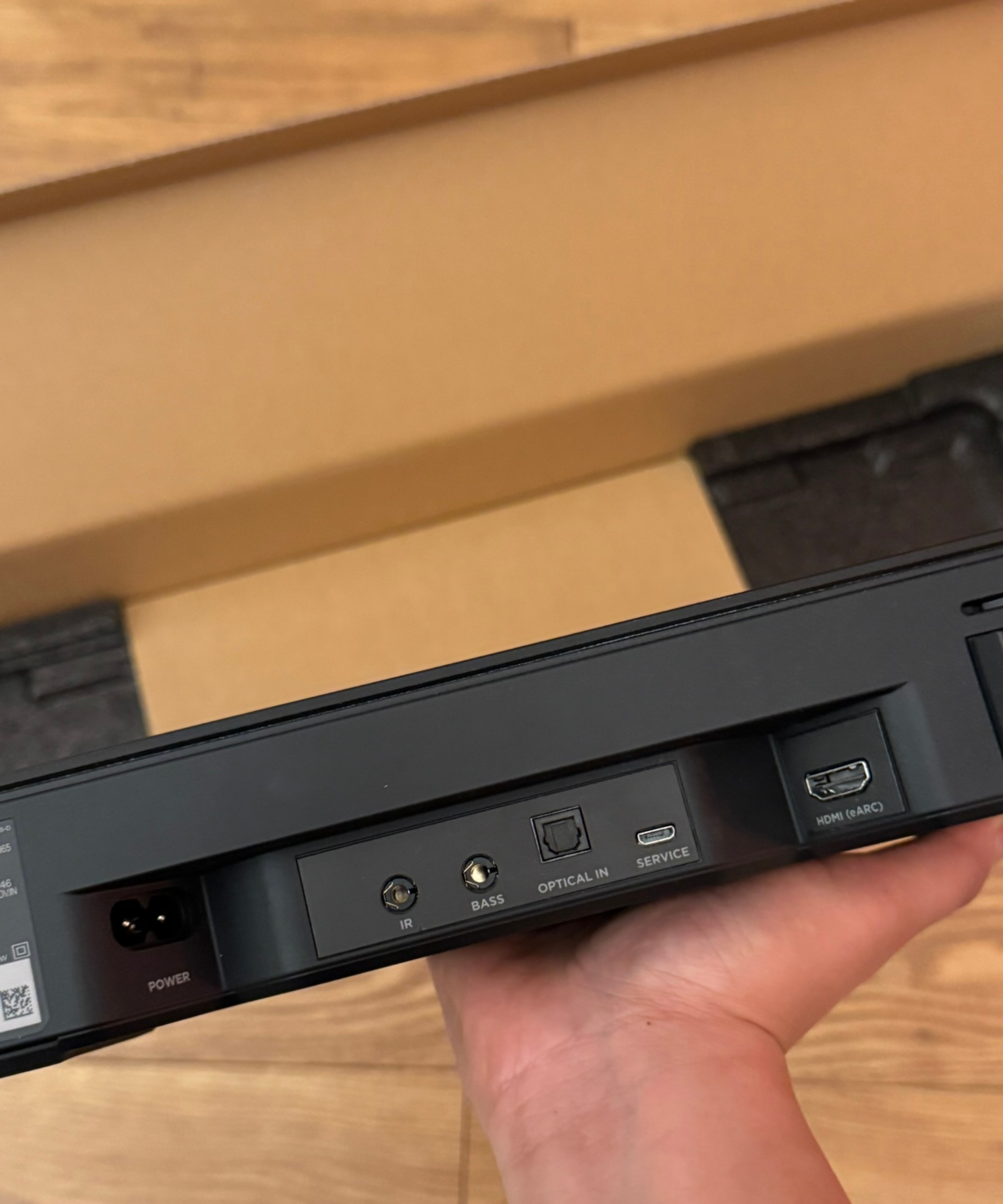Bose Smart Soundbar in Dan Fauzi's hand, held above cardboard packaging on wooden floor.