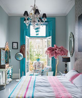 An example of bohemian bedroom ideas showing a bedroom in turquoise and pink with a globe and an ostrich feather lamp