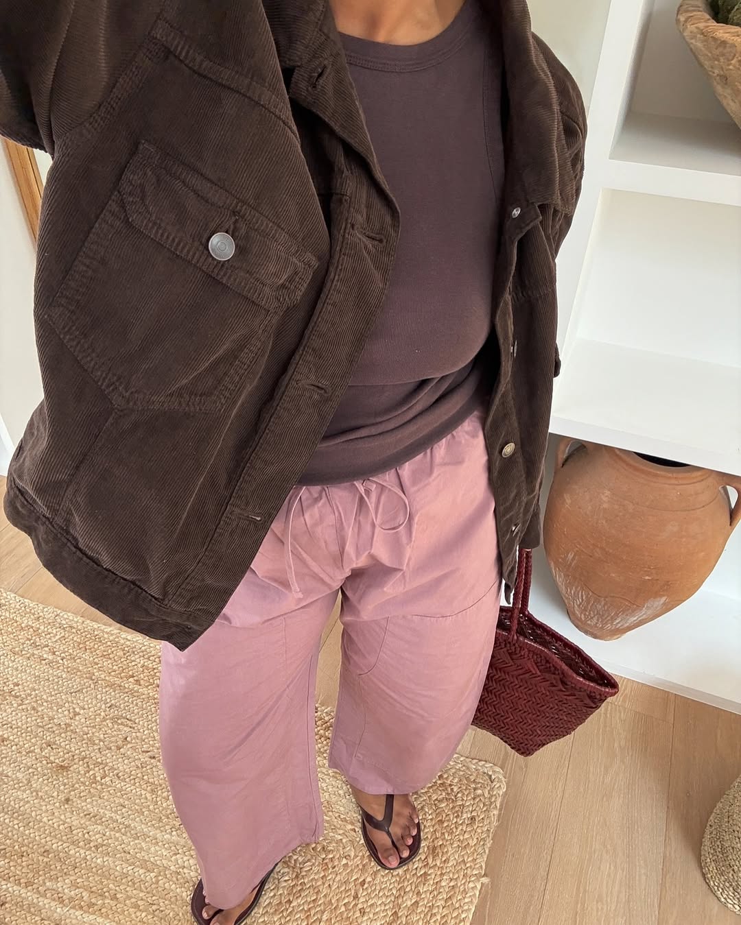 Monikh wearing a barely polished pedicure with pink trousers and a brown jacket
