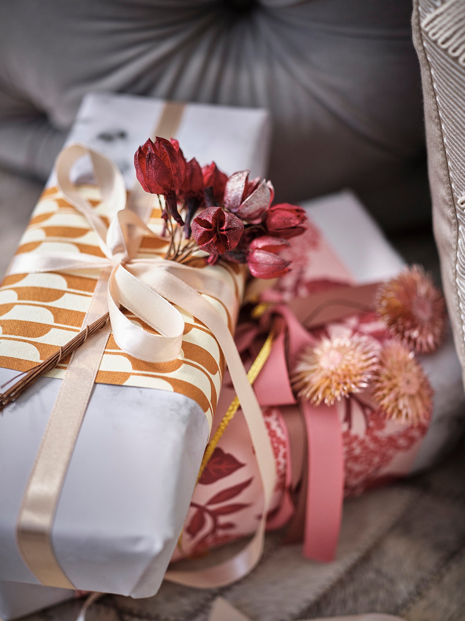 Close up of gift wrapped presents decorated with ribbons and dried flowers.
