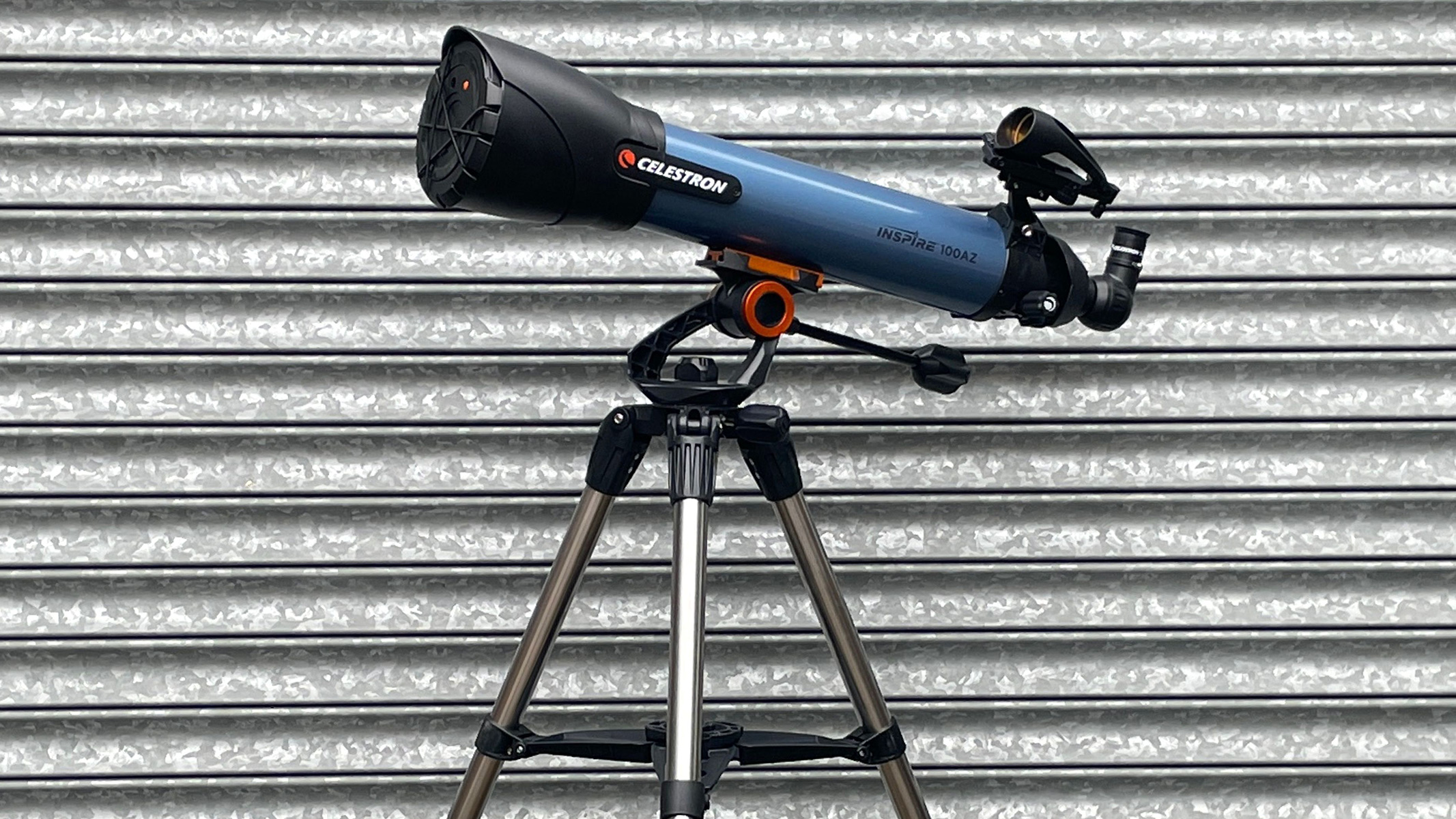 Side view of telescope on corrugated iron background