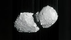 a grey, double-lobed rock on a black background. the surfaces of the two lobes are covered in boulders of various sizes