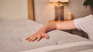 A hand tests the temperature control of the Leesa Studio Chill Mattress