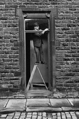 Man stood on step ladder fixing a door frame