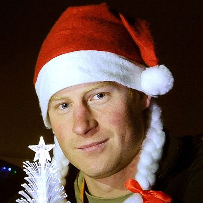 Prince Harry is cleanly shaven and wears a Christmas hat