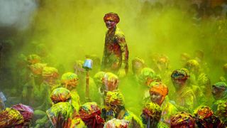 man standing above crowd at holi festival of colours