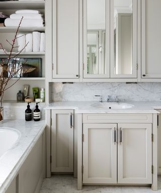 A cream bathroom with storage cabinets built into the vanity