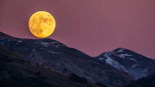 Beaver moon rising behind Gran Sasso d'Italia picks is seen from L'Aquila, Italy, on November 7, 2022.