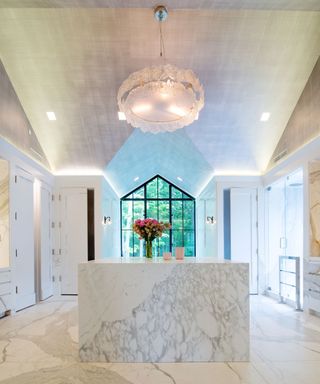 white bathroom with marble chandelier and wallpaper on high ceiling