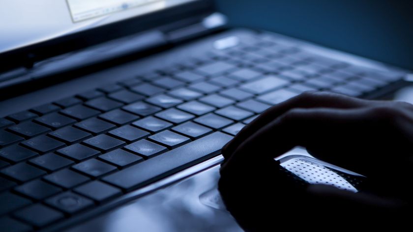 A hand on a keyboard in a dark room