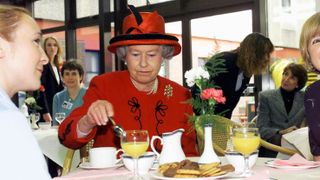 Queen Elizabeth II takes a tea break with hospital staff during her visit to Manchester Royal Infirmary on October 15, 1999