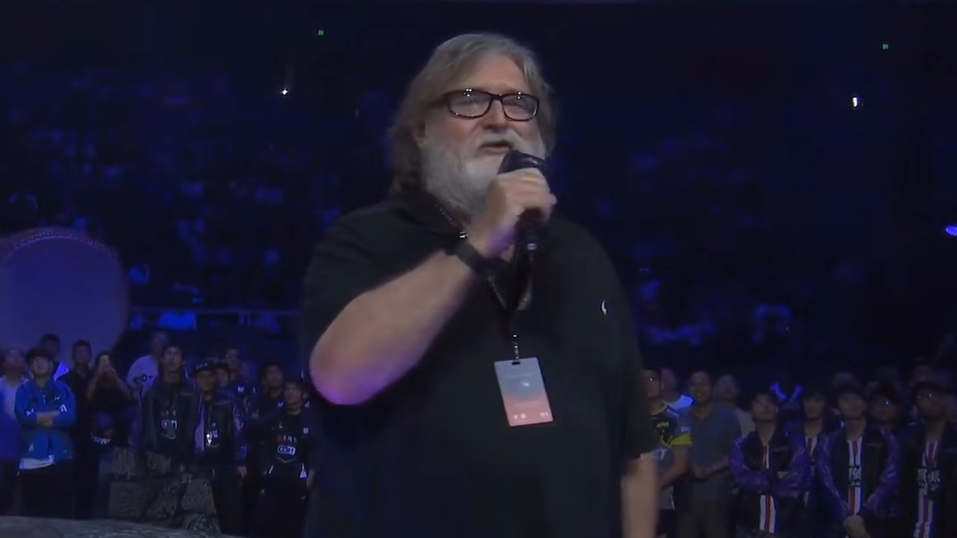 Gabe Newell in a black shirt holding a microphone