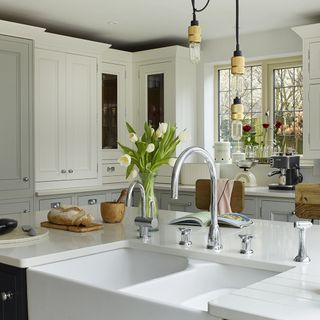 kitchen area with white kitchen cabinet and washbasin and white countertop