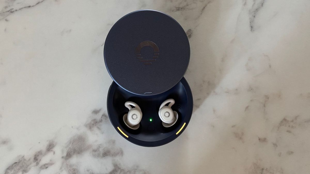 Image shows the white Ozlo Sleepbuds 2 in their battleship blue circular case, placed on a marble counter