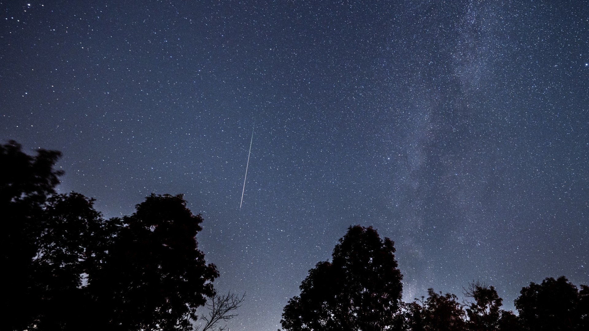 a streak of light in a starry night sky