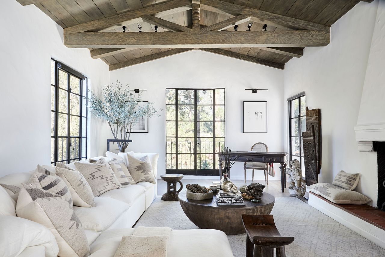 living room with neutral furnishings and white sofas and a beamed paneled ceiling round coffee table and multiple geometric print cushions on sofa