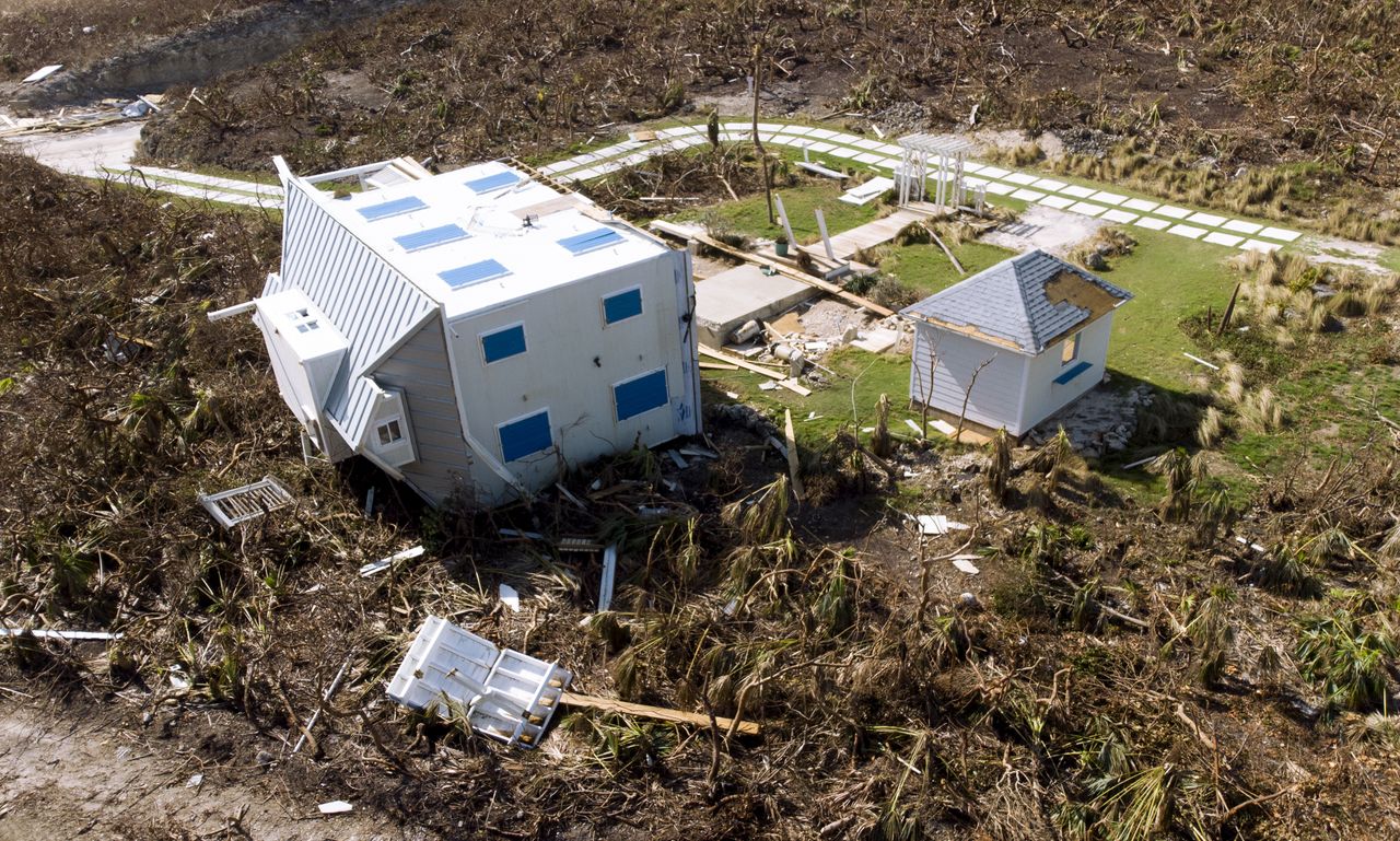 A house lies on its side among destruction