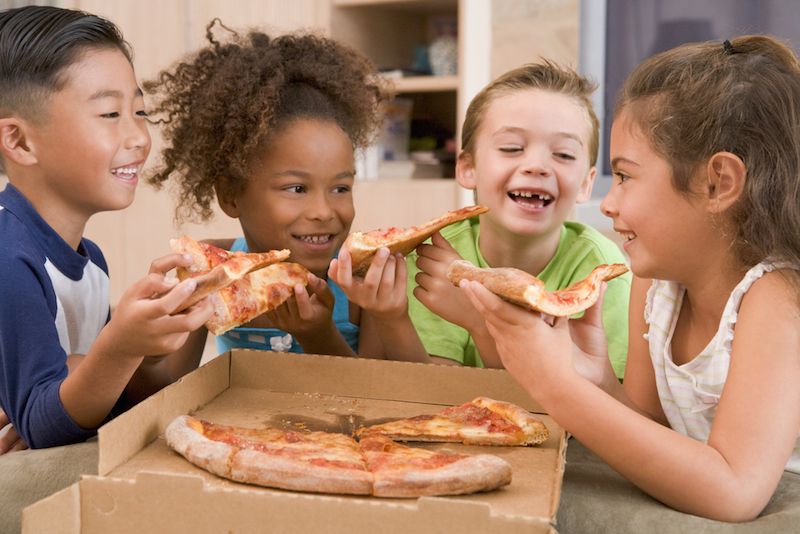 A group of children eat pizza.