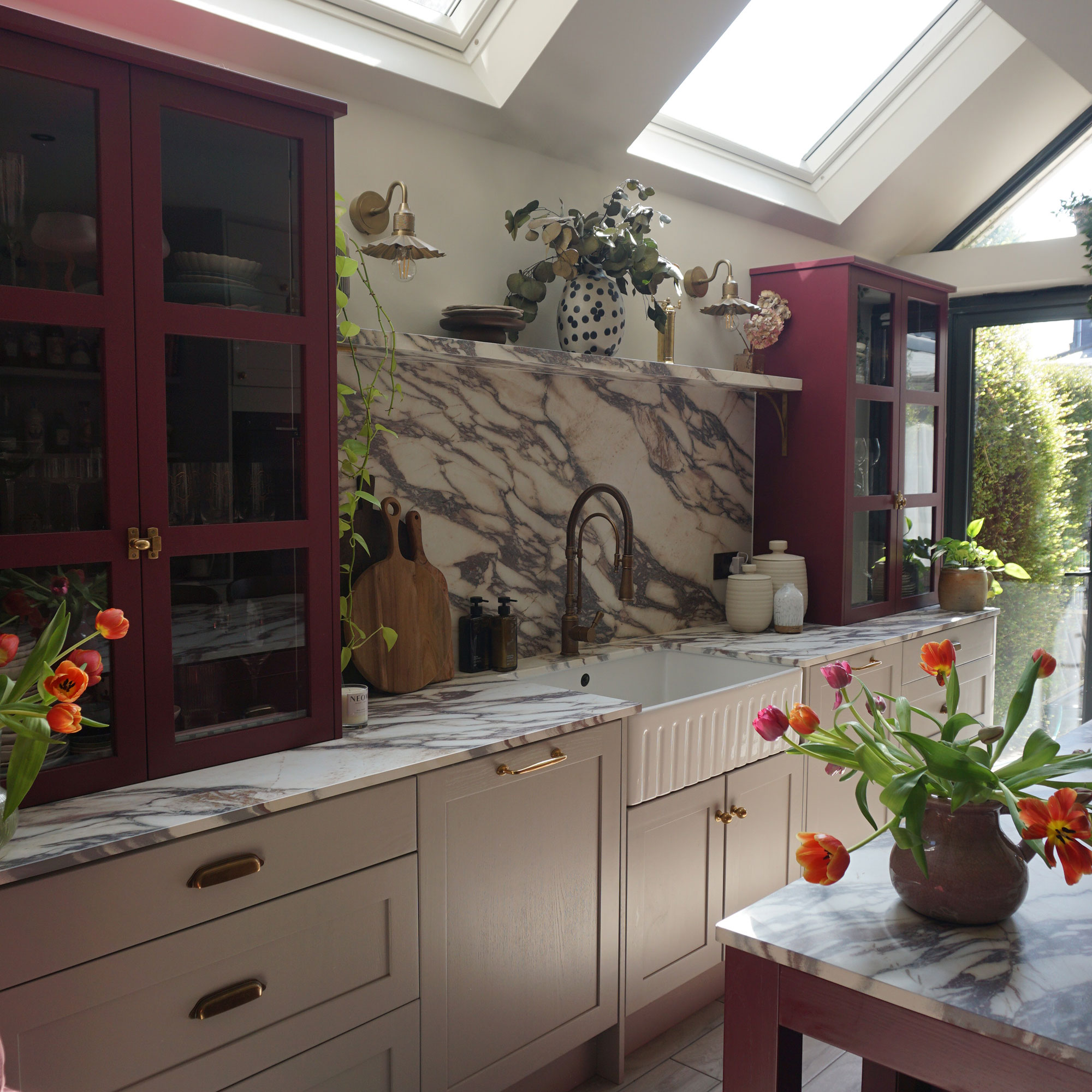 Marble kitchen worktop run with deep fluted Belfast sink, marble splashback and red cabinetry