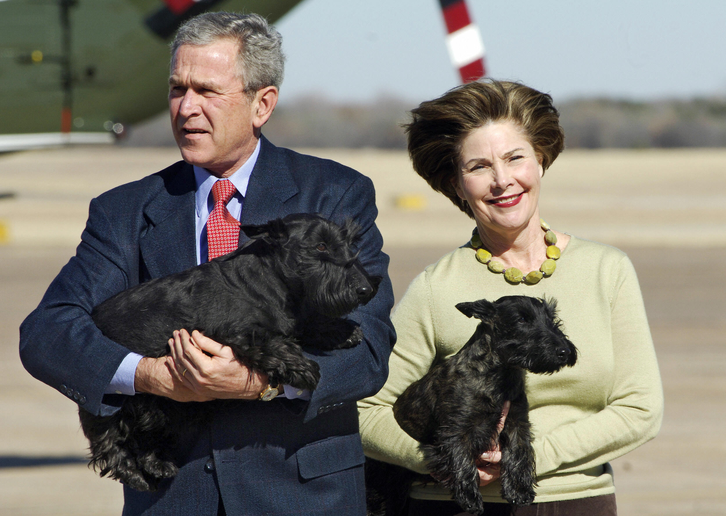 &lsquo;US President George W. Bush and his wife, Laura Bush, holding their Scottish terriers, Barney and Miss Beazley, after stepping off Air Force One on an airport runway in daylight, with the aircraft visible in the background.&rsquo;