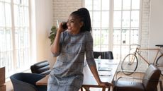 A Black businesswoman happily talking on the phone in front of a boardroom table