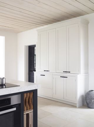 White cabinets and kitchen island surface, dark blue kitchen island base and door