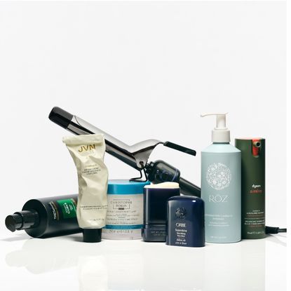 a selection of hair care products and a curling iron on a white background