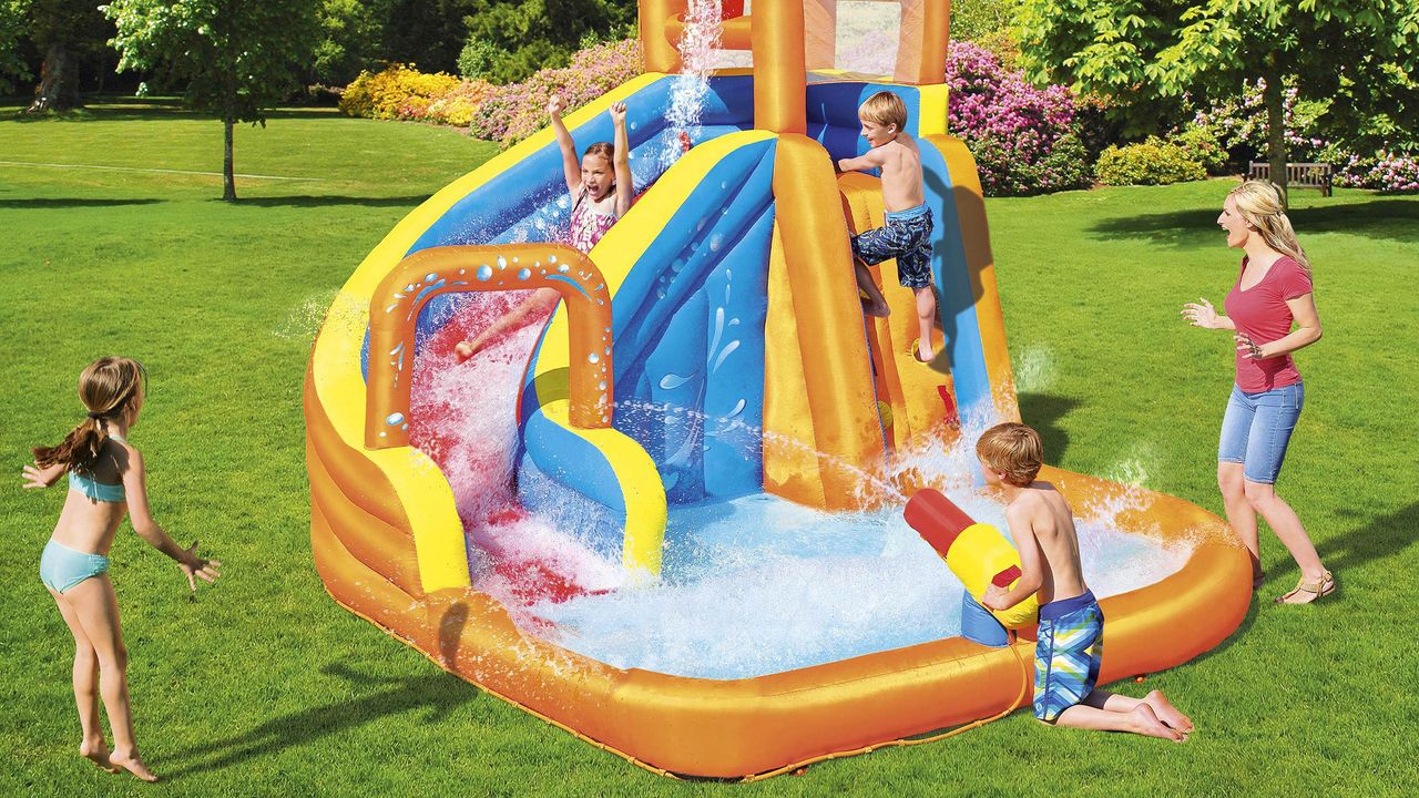 children playing in large orange paddling pool on a lawn