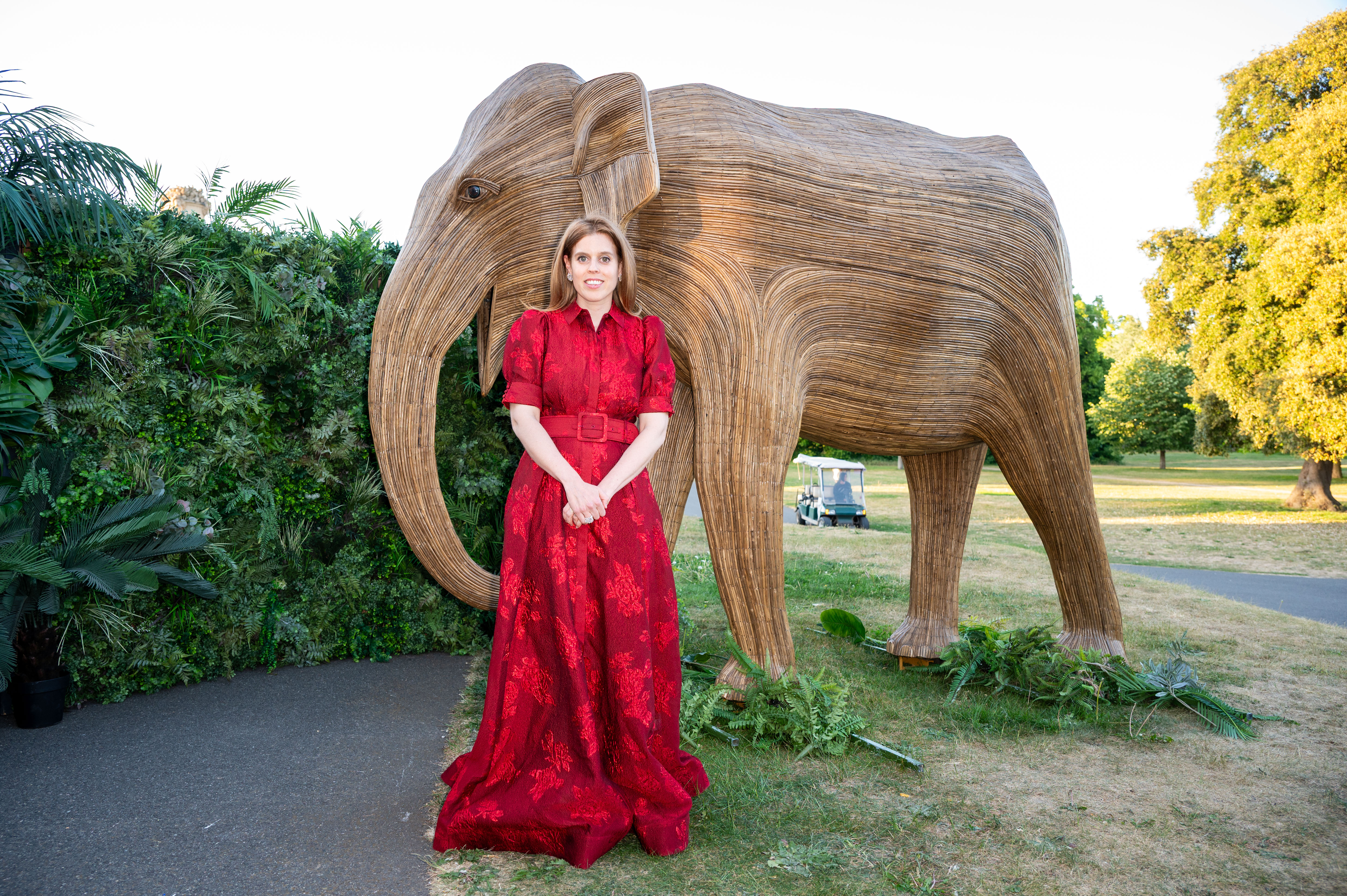 Princess Beatrice wearing a red gown standing in front of an elephant statue