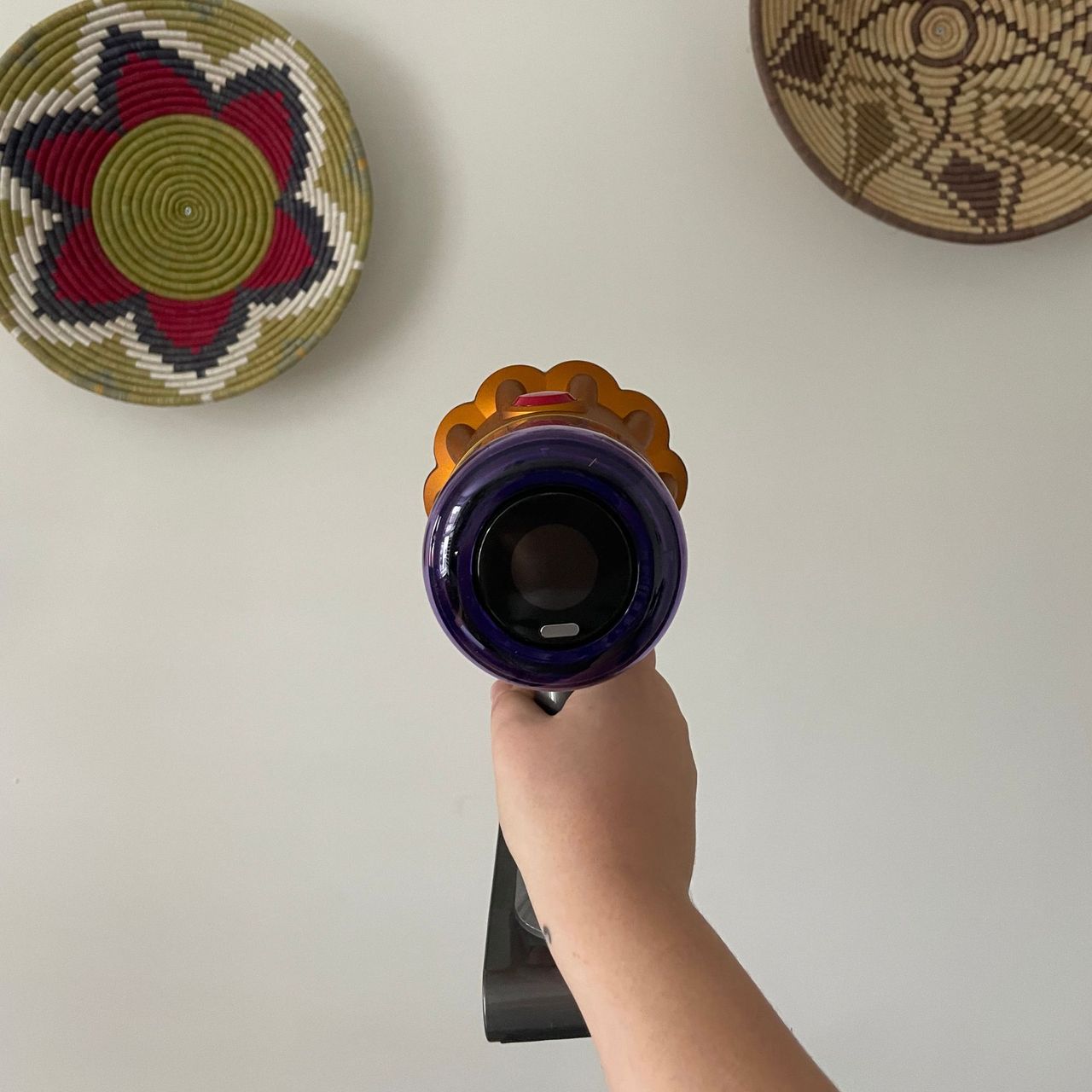Hand holding the Dyson V12 Detect Slim Absolute against a white wall