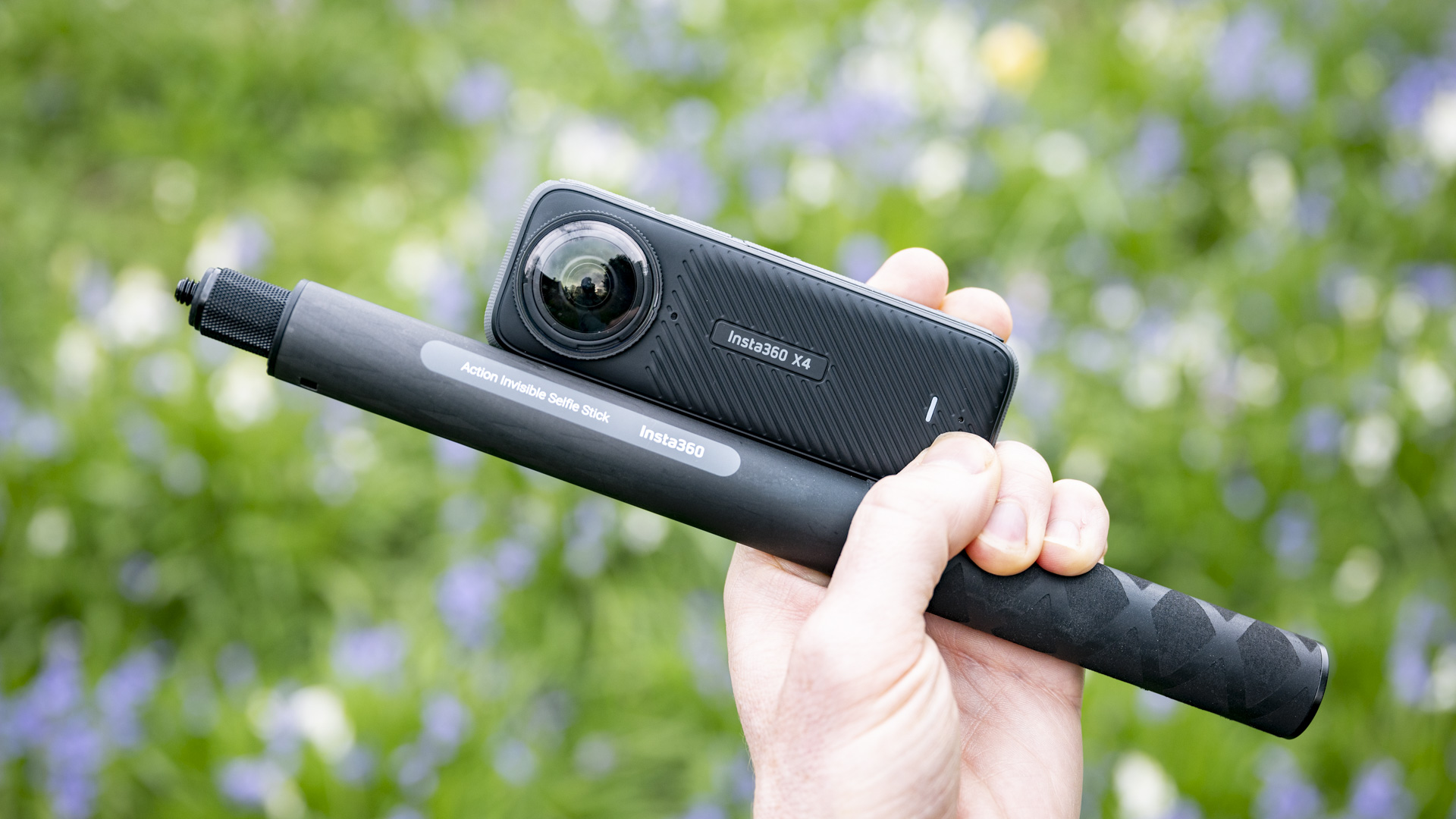 Insta360 X4 360 degree camera in the hand alongside selfie stick
