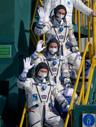 Soyuz MS-18 commander Oleg Novitskiy (at bottom) and flight engineers Mark Vande Hei (center) and Pyotr Dubrov wave from the launch pad prior to boarding their spacecraft at the Baikonur Cosmodrome in Kazakhstan on April 9, 2021.