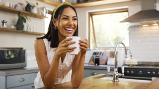 Happy woman drinking coffee in kitchen