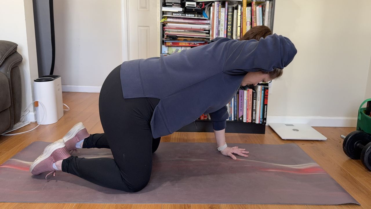 Jennifer Rizzuto performs a thoracic stretch. She is balancing on her knees and her left hand while her right hand is behind her head. Her elbow is pointing out to the side.