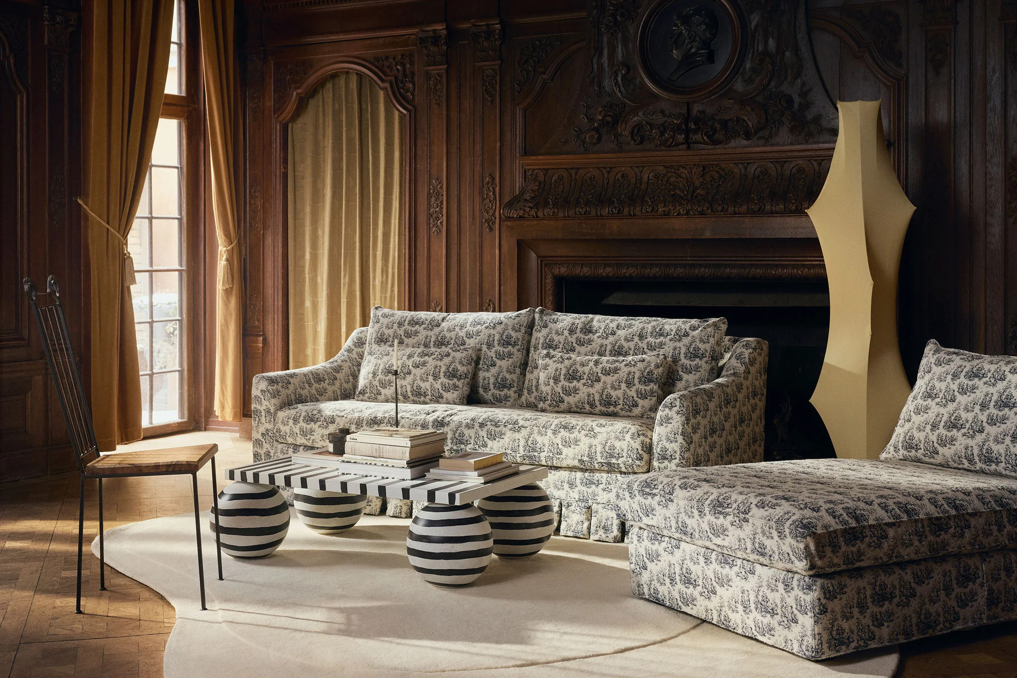 A stately room with two IKEA sofas with a toile slipcover, and a contemporary striped coffee table