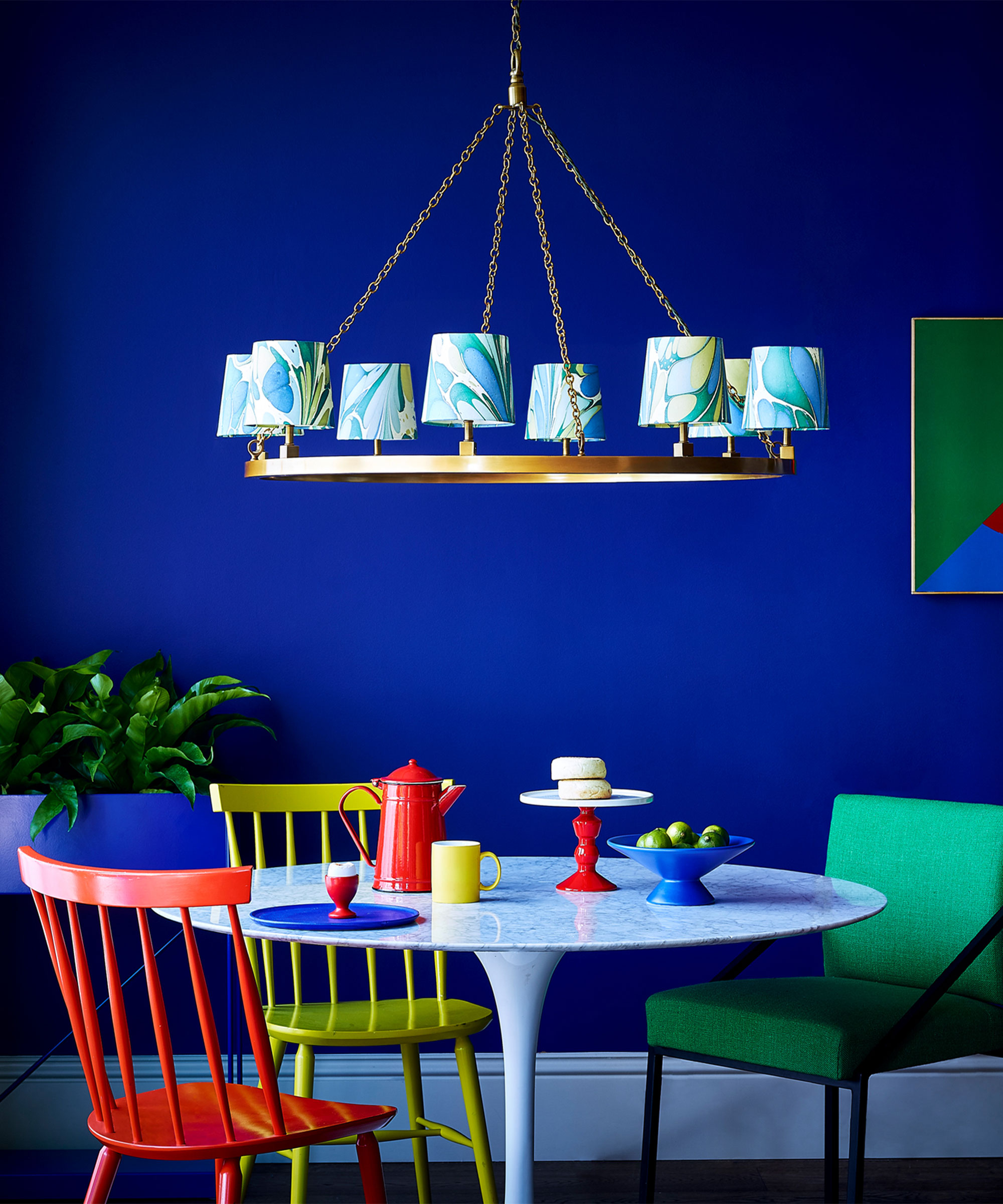 electric blue dining room with multicoloured dining chairs and marble paint effect chandelier