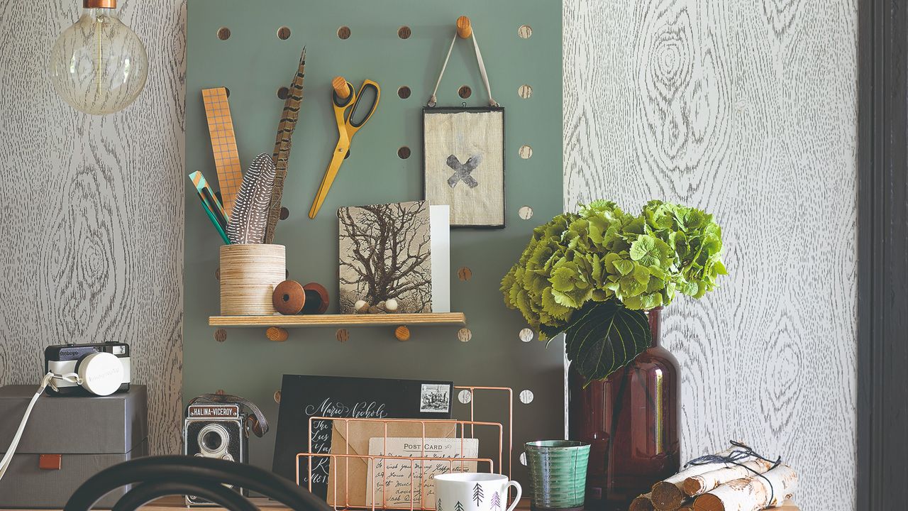 A home office with stationery on the desk and a vase of flowers