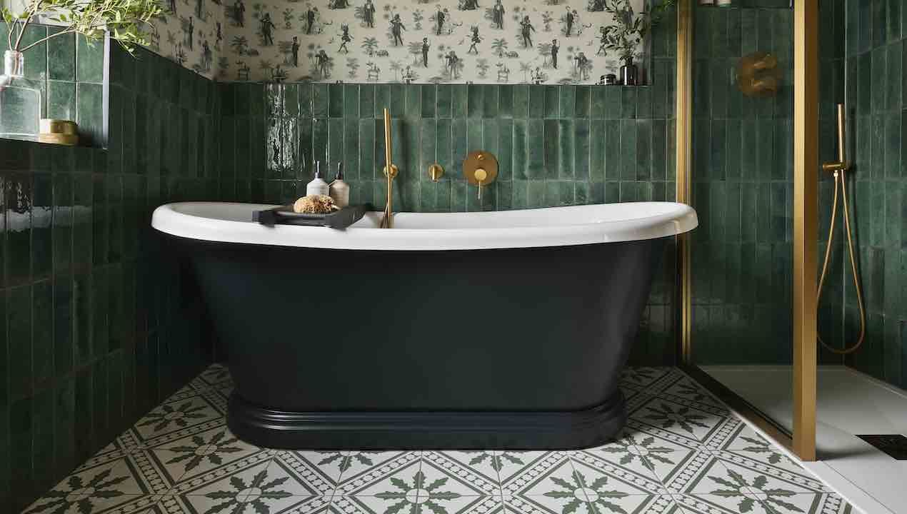 green bathroom with wallpaper and patterned tiles and freestanding bateau bath