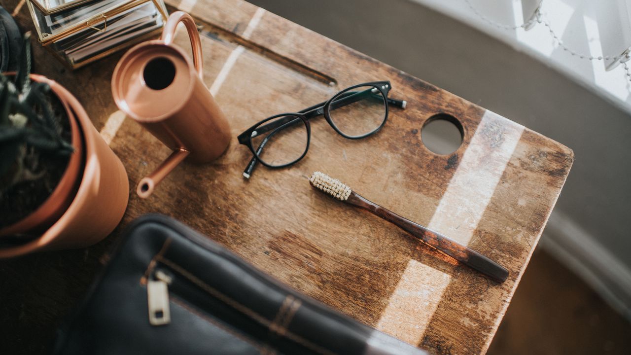 One of the best toiletry bags on a table, surrounded by a toothbrush, glasses, cactus and watering can