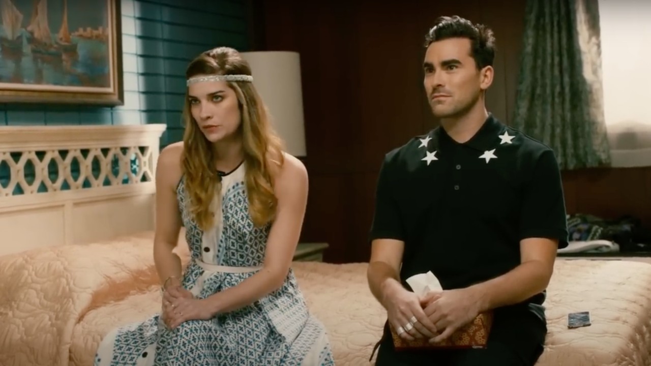 Annie Murphy and Dan Levy in a Schitt's Creek motel room scene talking to Eugene Levy and Catherine O'Hara.