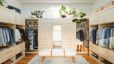 Neutral walk in closet with central ottoman on grey fluffy rug