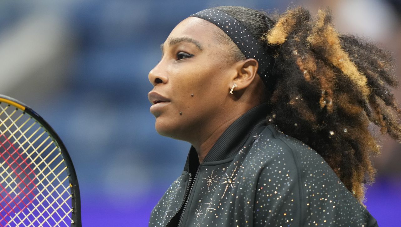 Serena Williams on the US Open Court wearing a black Nike sparkly jacket and holding a tennis racket