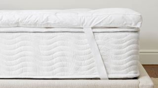 A closeup of the Saatva Down Alternative Featherbed mattress topper on a bed