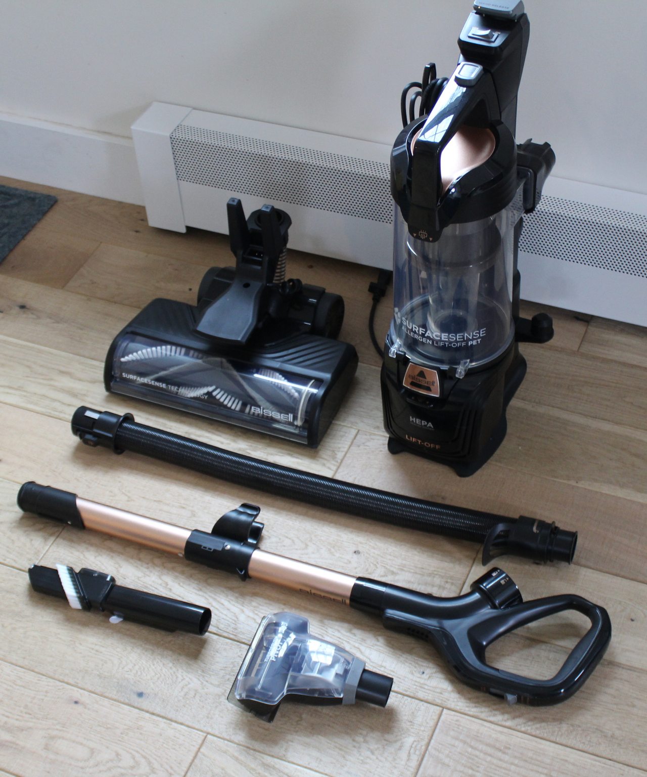 All unassembled parts of the Bissell SurfaceSense Allergen Pet Lift-Off Upright Vacuum on wooden floor in Camryn's home