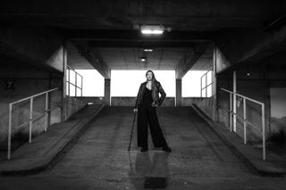 Black-and-white image of a person wearing a leather jacket and holding a cane, in an urban environment, taken on the Leica SL3-S with a Leica Summilux SL 50mm f/1.4 Asph lens