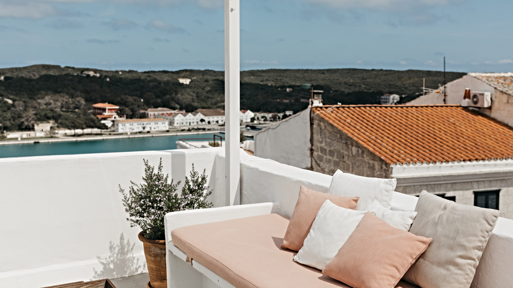 Padded bench with cushions on a roof terrace overlooking tiled roofs at Can Alberti 1740 hotel, Mahon, Menorca
