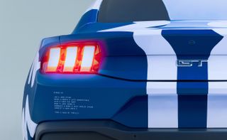 Photograph of the 60th year anniversary celebratory Mustang collaboration with Haus of Thrills. Close-up view of the rear of the Mustang in blue with two white vertical lines running through the middle.